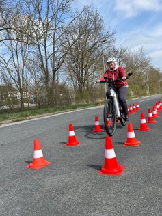Eine Frau fährt gerade durch eine Pylonen-Gasse. 