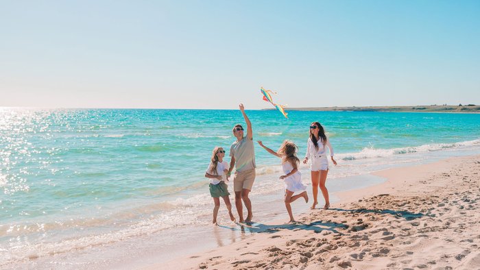 Eine glückliche Familie lässt am Strand einen Drachen steigen.