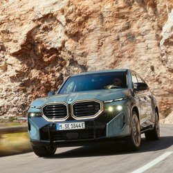 BMW fährt auf einer Straße durch eine bergige Landschaft.