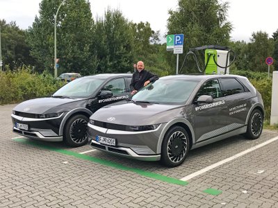 Mann zwischen zwei Hyundai Autos an einer Ladesäule.