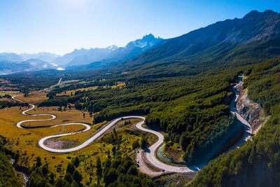 Straße schlängelt sich in vielen Windungen durch eine weite Berglandschaft.