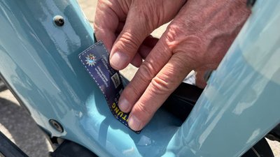 Ein blauer Registrierungsaufkleber wird auf ein Fahrrad geklebt. 