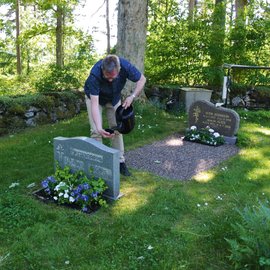 Ein Mann, der ein Grab gießt.
