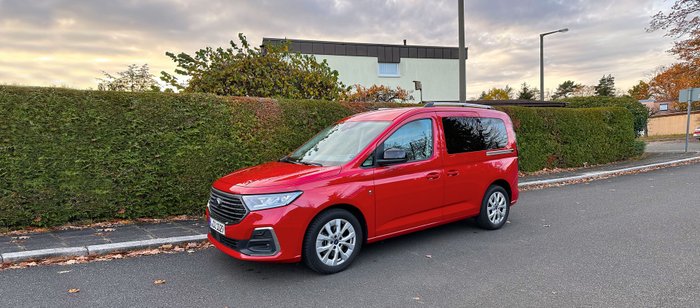 Ein roter Ford Tourneo parkt am Straßenrand.