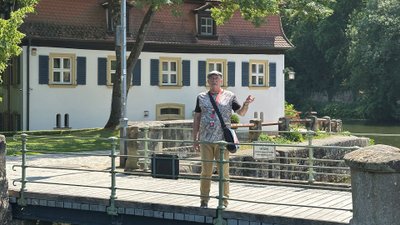 Mann steht auf Brücke mit alter Mühle und Wasser im Hintergrund.