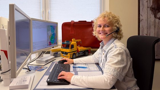 Eine Frau mit Headset sitzt an einem Schreibtisch mit zwei Bildschirmen.