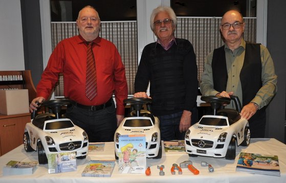 Drei Männer, Rutschautos auf dem Tisch.