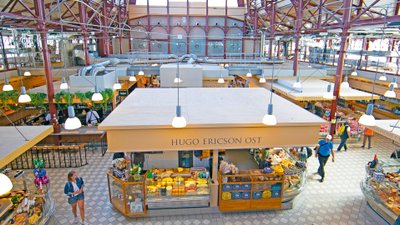 Blick auf eine Markthalle mit verschiedenen Ständen und einer Glas-Stahl-Konstruktion als Dach