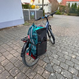 Eine Reisetasche steckt in der Tasche Easy Exo Max an einem Fahrrad.