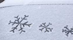 Schneebedeckte Autoscheibe mit Schneeflockensymbolen.