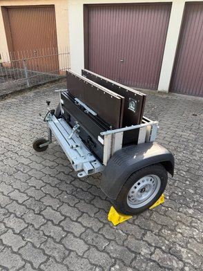 Zusammengefalteter Faltos-Anhänger steht in einer Einfahrt. 