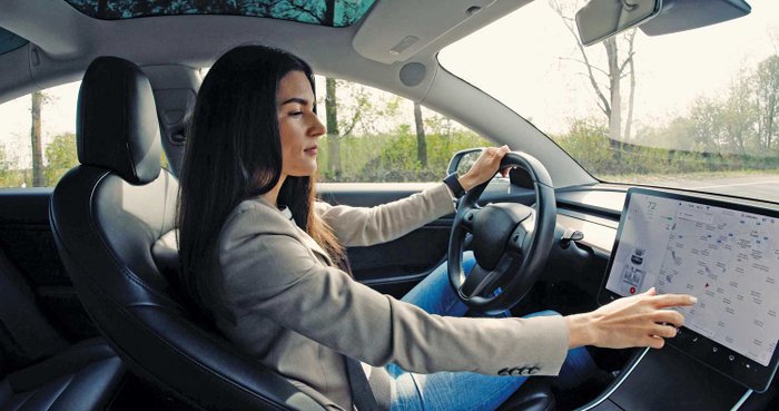 Eine Autofahrerin schaut während der Fahrt auf einen Touchscreen.