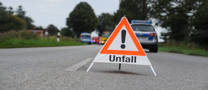 Ein Warndreieick mit dem Hinweis "Unfall" steht auf der Straße.