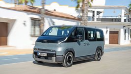Kia PV5 fährt auf einer Straße. 