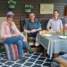 Zwei Männer und eine Frau sitzen am Tisch.