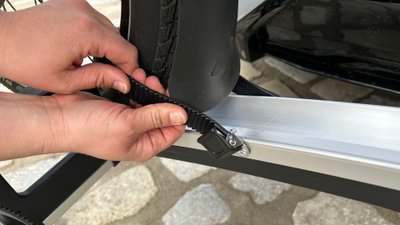 Frau hält Gurt eines Fahrradträgers in der Hand.