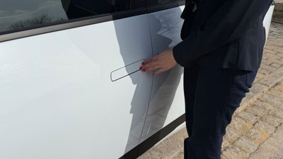 Frau steht vor Fahrzeug mit versenktem Türgriff. 