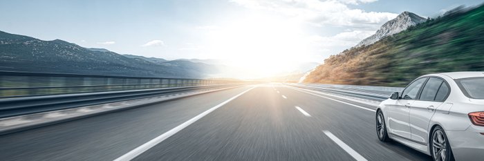 Auto fährt auf einer Autobahn bei tiefstehender Sonne.