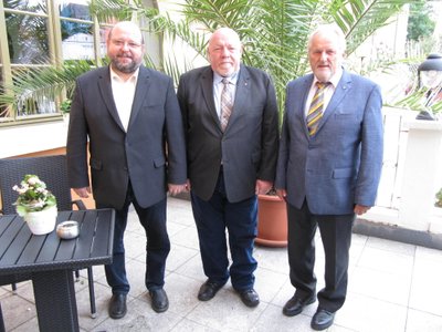 Drei Männer in dunklen Anzügen.