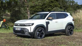 Weißer Dacia Jogger von der Seite, im Hintergrund Bäume.