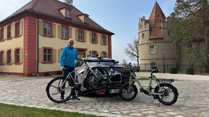 Wolfgang Sievernich steht mit Fahrrädern vor einem Auto. 
