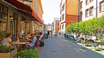 Blick auf eine kopfsteingepflasterte Gasse mit alten Gebäuden und Gastronomie mit Außenplätzen