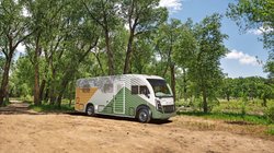 Thor Test Vehicle parkt auf festgestampfter Erde vor hohen grünen Bäumen.