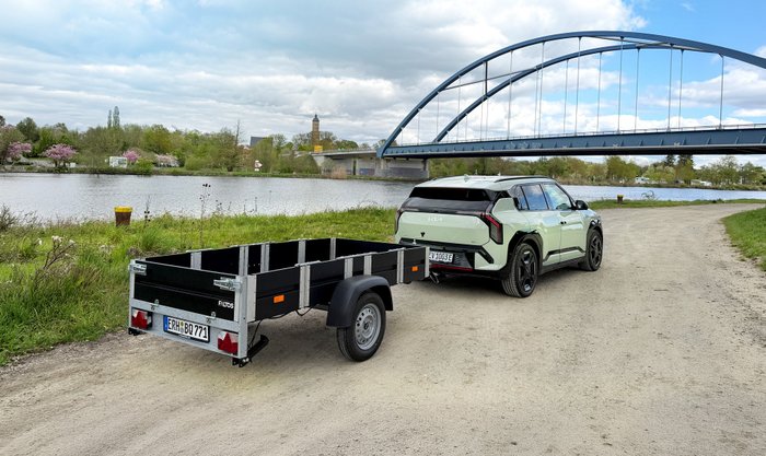 Faltos-Anhänger steht mit Kia EV3 vor einem Fluss. 