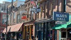 Belebte Straße mit Leuchtreklamen von Musikclubs und Restaurants.