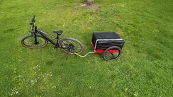 Der Fahrradanhänger Hinterher Hmax light mit der Falttasche auf einer Wiese mit Fahrrad 