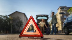 Ein Warndreieck ist vor einem verunfallten Auto aufgestellt. 