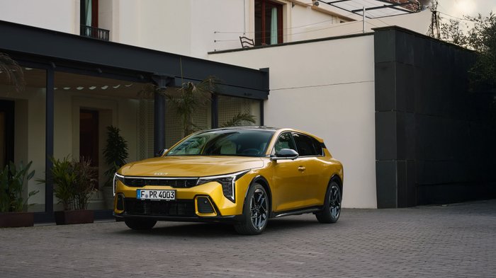 Gelber Kia K4 steht vor einem Gebäude.