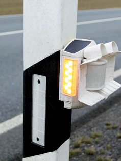 Sensor für Wildwarnung an einem Leitpfosten in Nahaufnahme.
