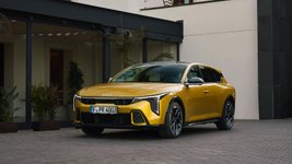 Gelber Kia K4 steht vor einem Gebäude.