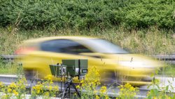 Ein gelbes Auto fährt in eine Geschwindigkeitskontrolle. 