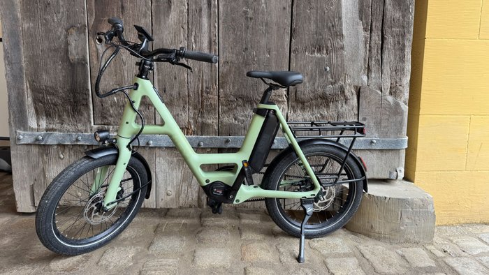 Grünes Fahrrad steht vor einer Holzwand