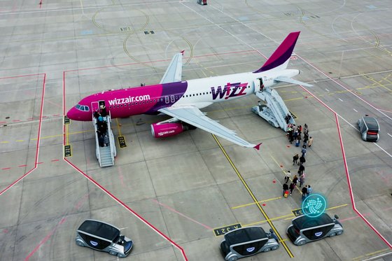 Flugzeug steht auf dem Vorfeld, EDAG Citybots transportieren Passagiere. 