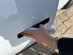 Frau öffnet den Türgriff des Kia EV4. 