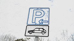Ein Parkplatzschild mit einem Autosymbol darunter.