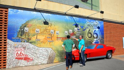Zwei Männer stehen vor einem Wandgemälde, das den Streckenverlauf der Route 66 darstellt.