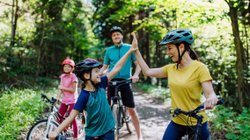 Eine Familie ist im Wald auf Fahrrädern unterwegs. 