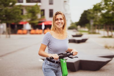 lachende Frau auf einem E-Scooter.