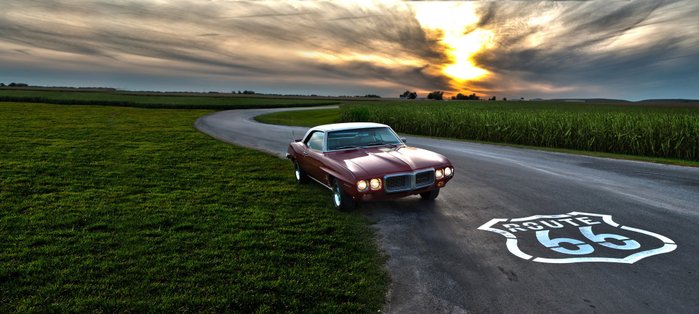 Classic Car am Rand einer Straße mit Route-66-Symbol auf dem Asphalt.