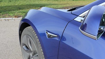 Kamera an der Fahrerseite eines blauen Teslas.