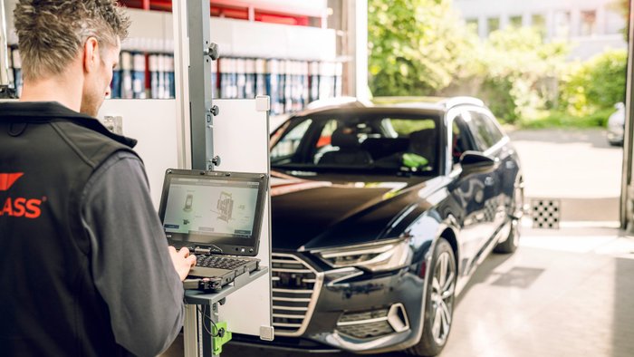 Mann steht an Diagnosegerät vor einem Auto.