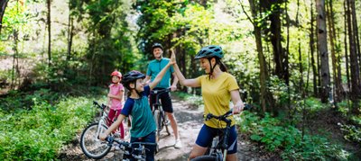 Eine Familie ist im Wald auf Fahrrädern unterwegs. 