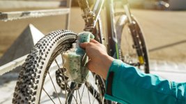 Frau putzt Fahrrad mit einem Schwamm. 