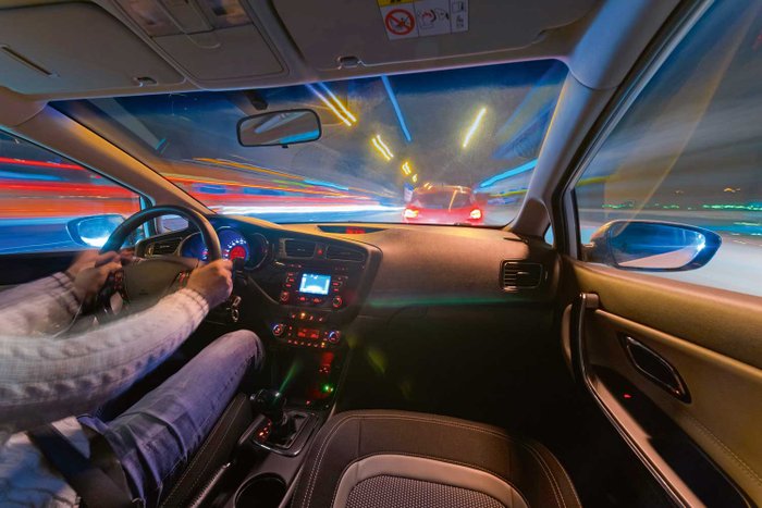 Blick aus dem Auto-Cockpit auf eine nächtliche Straße.