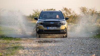 Subaru Forester fährt durch eine große Pfütze, das Wasser spritzt zur Seite.