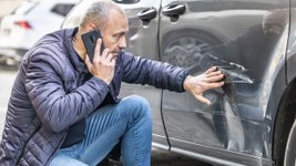 Mann begutachtet Schaden an seinem Auto. 